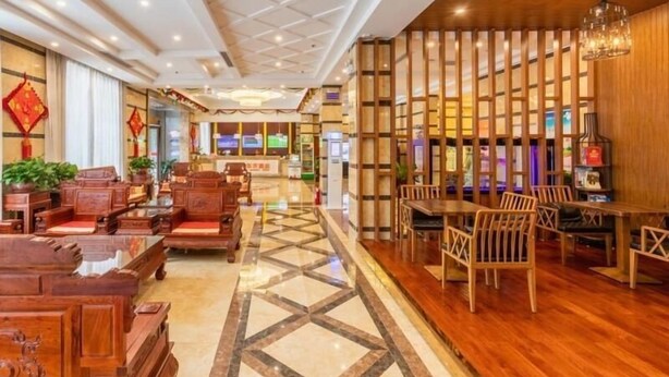 Un hall d’hôtel avec des meubles en bois, un comptoir d’accueil et un sol à motifs.