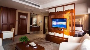 Un hall d’hôtel comprenant un espace salon, un téléviseur fixé sur un panneau en bois, un comptoir de réception et une porte donnant accès à une salle de bain.