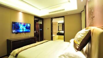 Hotelkamer met een groot bed, een flatscreen televisie aan de muur, een nachtkastje en een deur naar de badkamer.