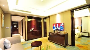 Een hotelkamer met een bank, een televisie op een kast en een vloerkleed met een bloemendesign.
