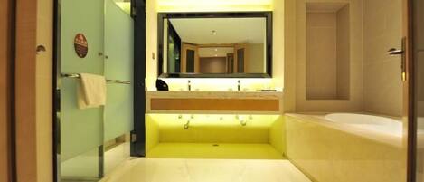 Un baño moderno con un espejo grande, un lavamanos amarillo y una bañera.