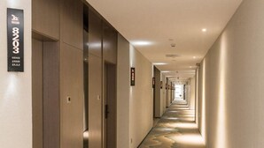 En hotellkorridor med ett långt, smalt utrymme, med en rad dörrar på ena sidan och ett mönstrat golv.