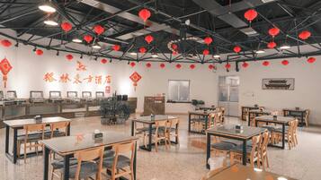 A restaurant with tables and chairs, red lanterns hanging from the ceiling, and a wall with Chinese characters.