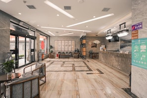 A spacious lobby with a reception desk, seating area, and artwork on the walls.