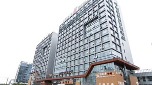 A multi-story hotel with a modern glass facade, featuring a prominent signage at the top. - Jinjiang Inn (Suzhou)