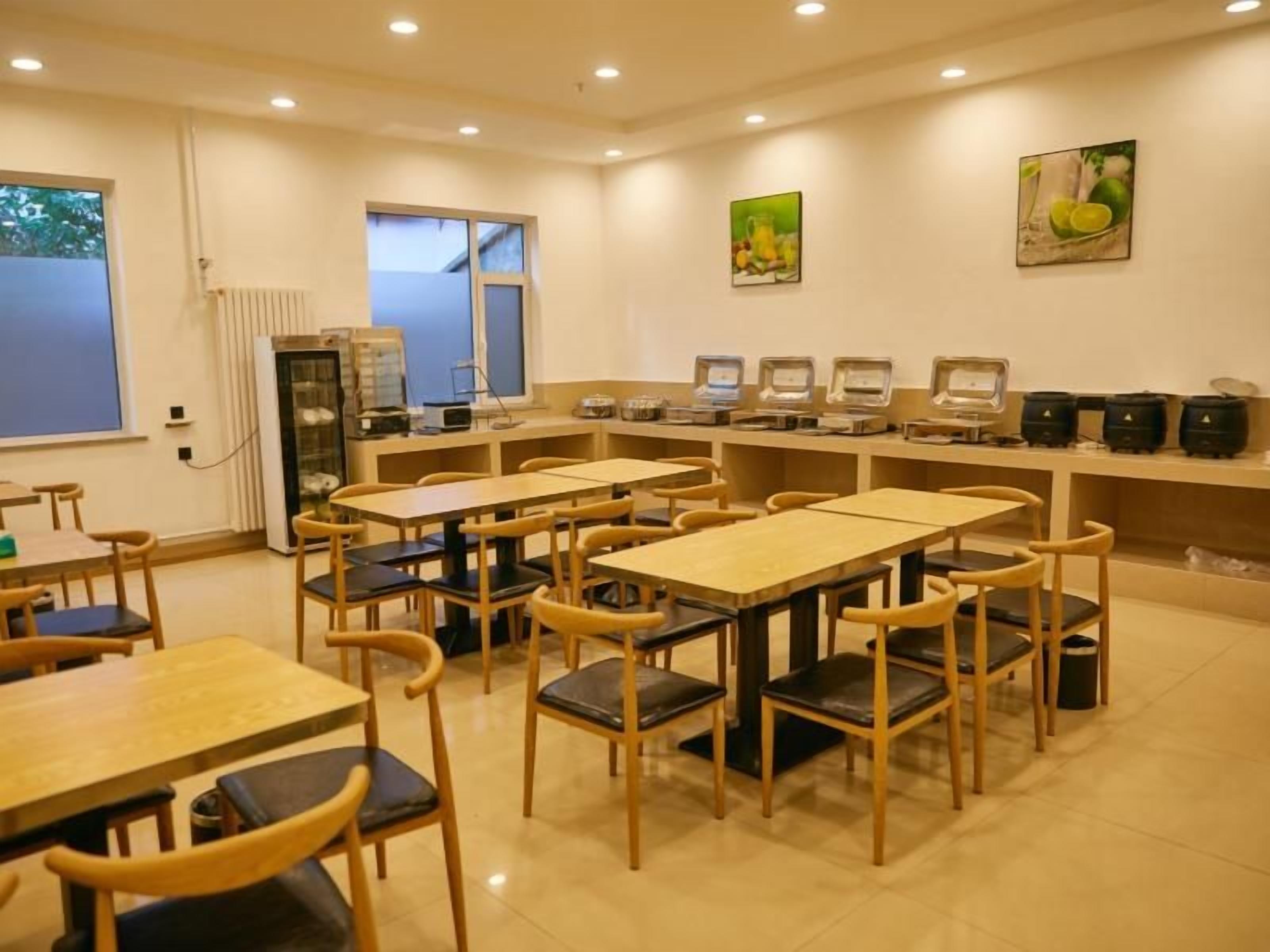 A dining area with multiple tables and chairs, a kitchen area with appliances, and artwork on the walls.