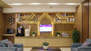 A modern lobby with a reception desk, a flat-screen TV, and two sofas. - Greentree Inn Shanghaibaoshan District Tieshan Road Youyi Road Hotel (Shanghai)