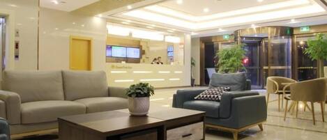 A modern lobby with a reception desk, sofas, and a coffee table.