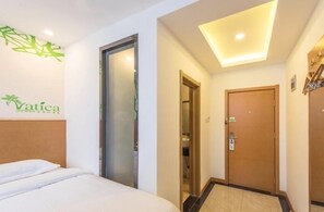 A hotel room with a bed, a door, a wall-mounted logo, and a ceiling light. - Vatica Tianjin Nankai Hardware Market West Jieyuan Road Hotel (Tianjin)