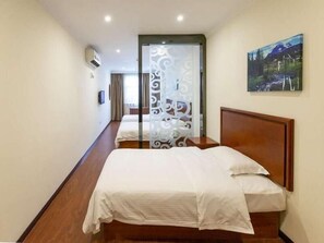 A hotel room with two beds, a wooden floor, a decorative partition, and a painting on the wall. - Greentree Inn Xinghua Middle Yingwu Road Express Hotel (Taizhou)