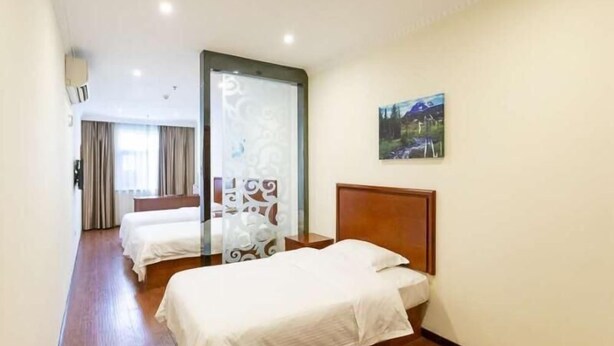 A hotel room with two beds, a wooden floor, a glass partition, and a painting on the wall. - Greentree Inn Xinghua Middle Yingwu Road Express Hotel (Taizhou)
