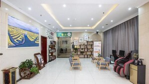 A hotel lobby with a reception desk, seating area, massage chairs, and a large painting on the wall. - Greentree Inn Xinghua Middle Yingwu Road Express Hotel (Taizhou)