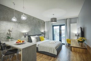 A modern hotel room with a bed, a dining area, and a view of the outdoors. - Rajska 3 by PI Apartments (Kraków)