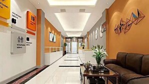 A hotel lobby with a modern design, featuring a reception desk, seating area, and a decorative wall with geometric patterns. - Shell Tai'an Taishan District Xinhuacheng International Plaza Hotel (Tai'an)