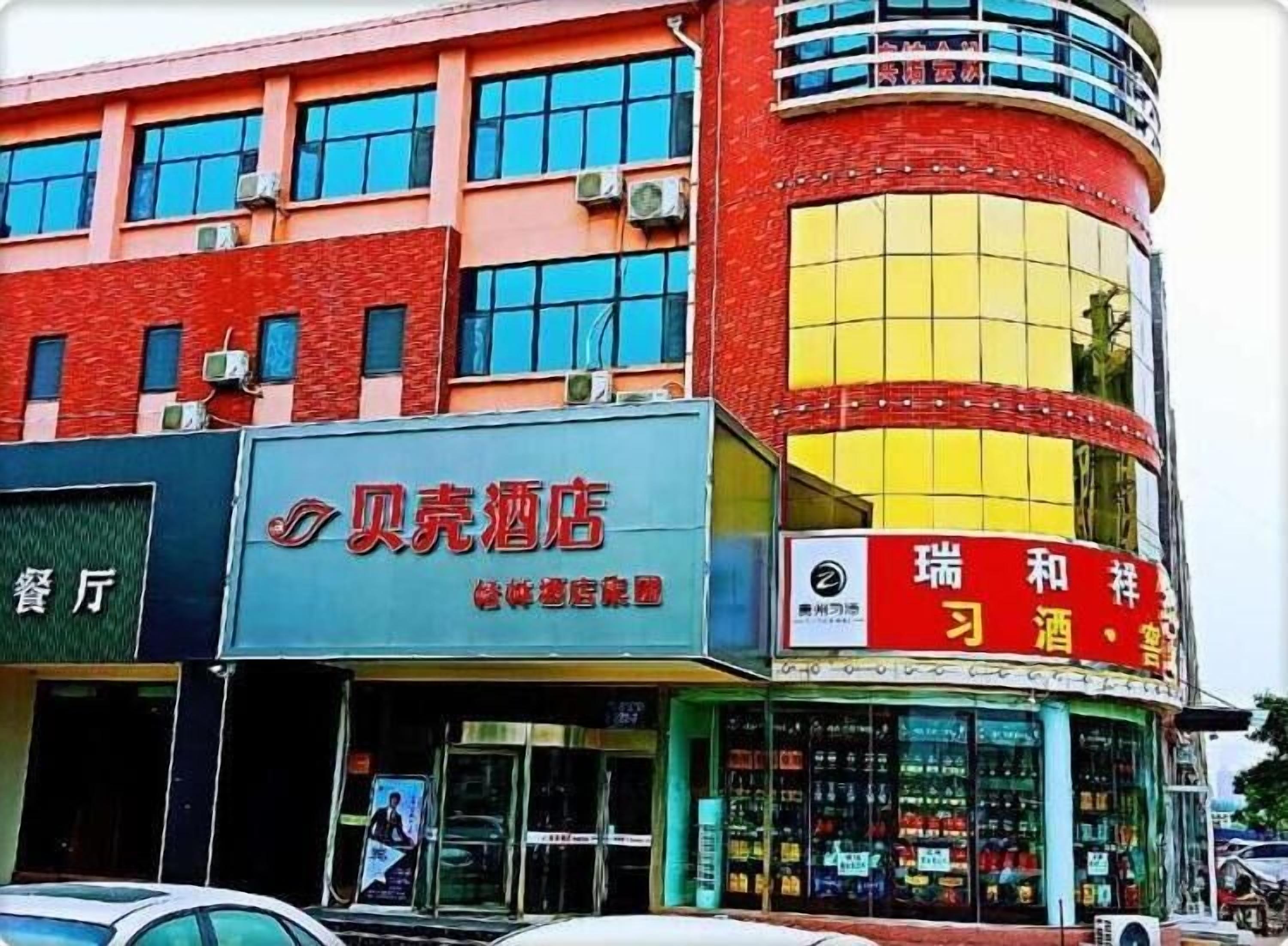 Un hotel con un letrero que dice 'Beike Hotel' y otro letrero que anuncia 'Vino y Cerveza de Sichuan'.