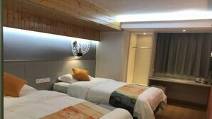 Ein Hotelzimmer mit zwei Betten, einer Holzbalkendecke, einer Wandleuchte und einem Fenster mit Vorhängen.