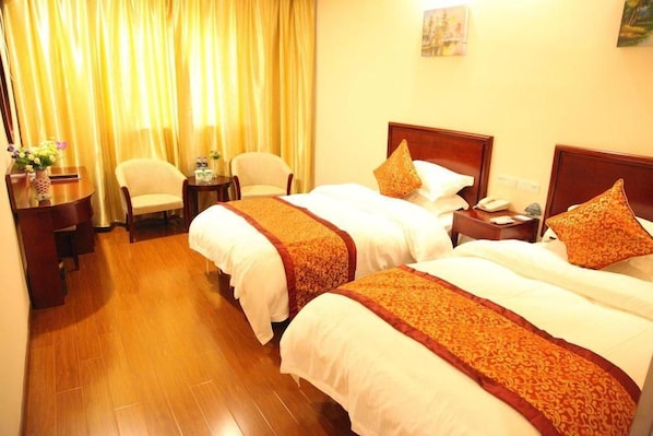 Quarto de hotel com duas camas, uma escrivaninha, cadeiras e cortina.