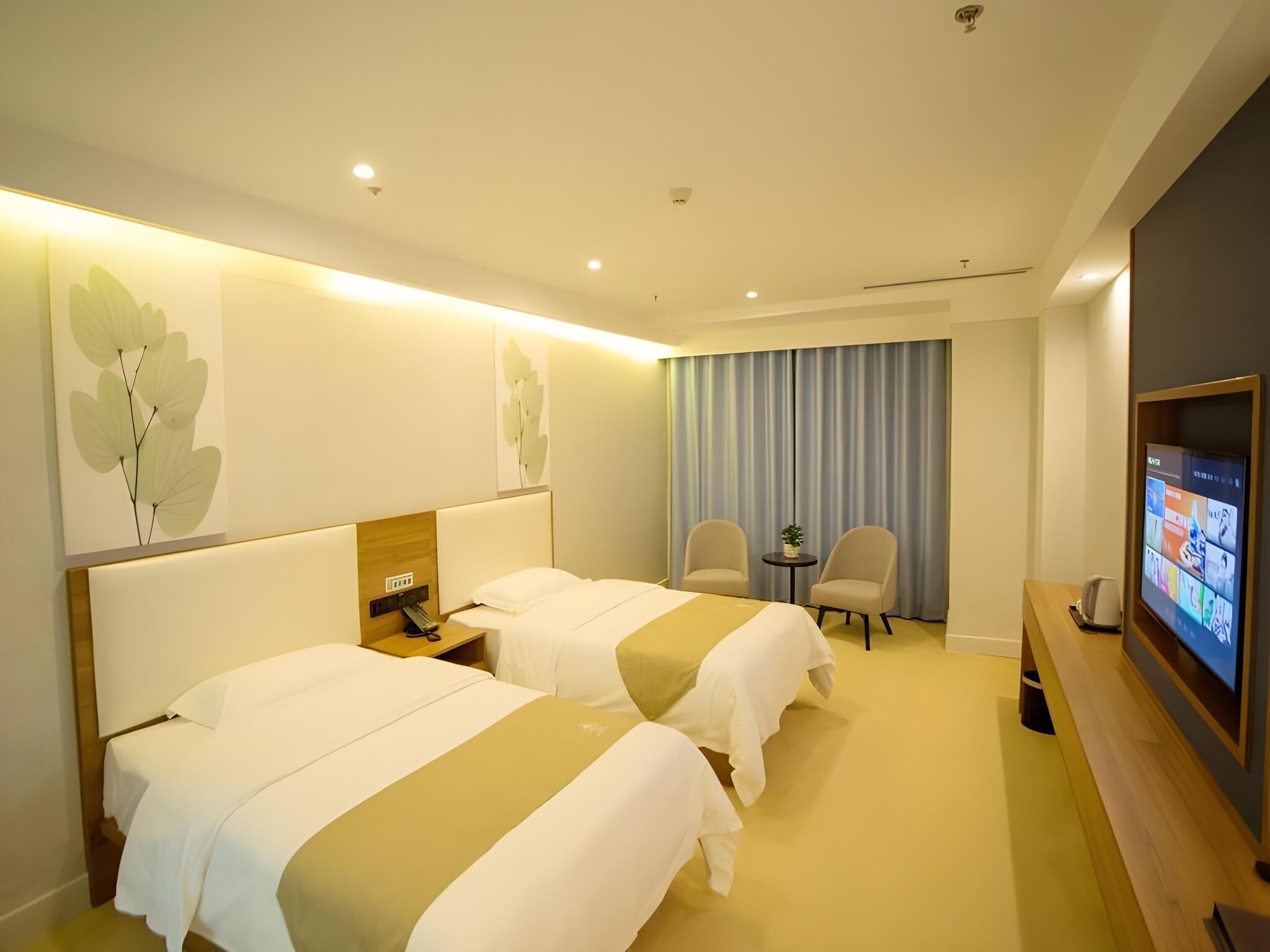 A hotel room with two beds, a TV, a desk, and a chair.