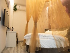 A bedroom with a bed, a bedside table, a TV, and a wall-mounted air conditioner.