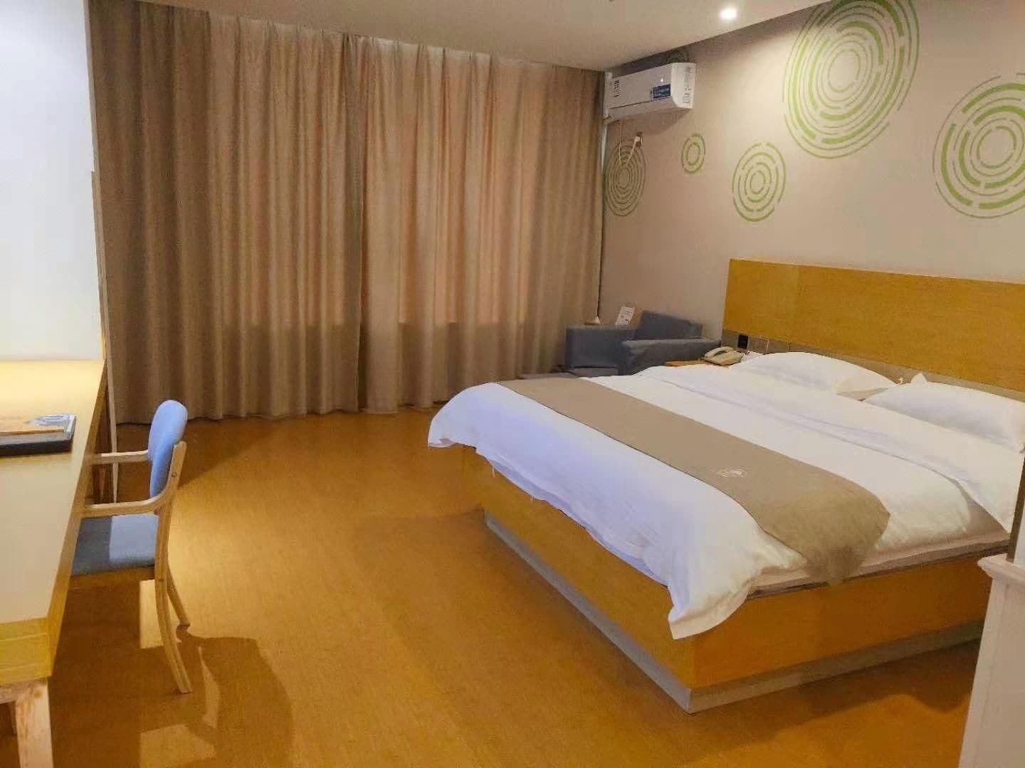 Una habitación de hotel con cama, escritorio, silla y cortina.