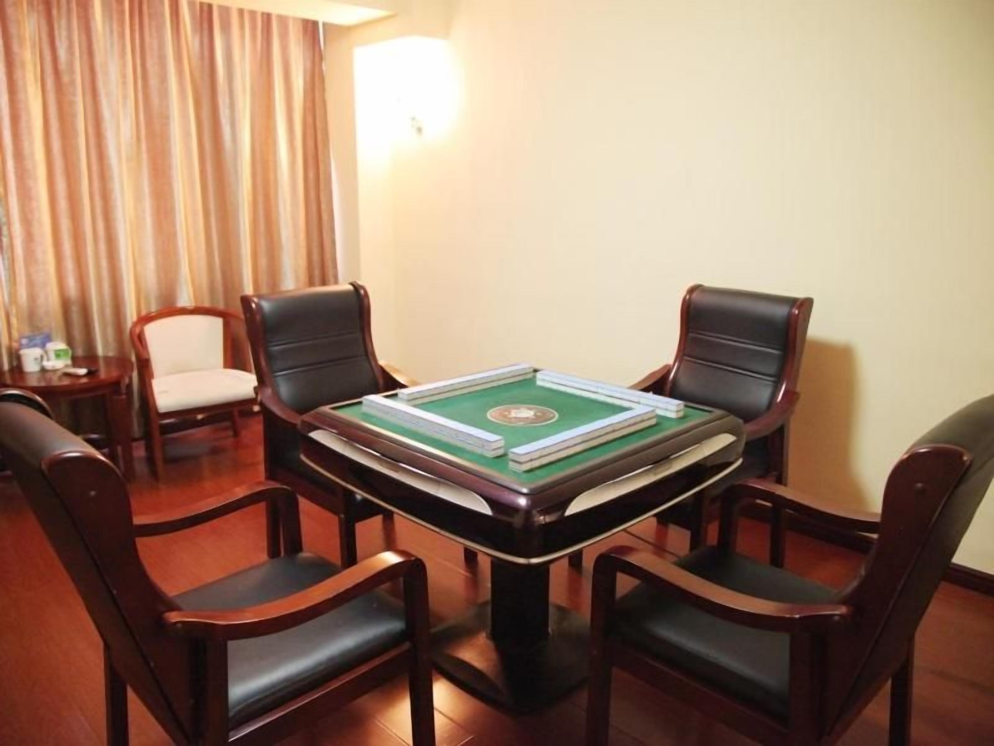 A room with a green snooker table, four wooden chairs, a small table with cups, and a curtain.