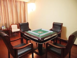 A room with a green snooker table, four wooden chairs, a small table with cups, and a curtain.