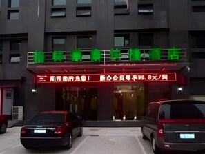 A building with a red awning and a sign in a foreign language. There are two cars parked in front. - Greentree Inn Handan Train Station Express Hotel (Handan)