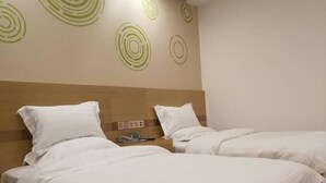 Une chambre d’hôtel avec deux lits, chacun doté de draps et d’oreillers blancs. On y trouve une tête de lit en bois et un mur orné de motifs circulaires.