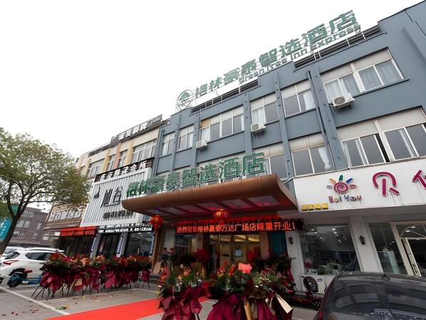 Ein Hotel mit moderner Fassade, mehreren Etagen und einem auffälligen Eingang mit rotem Teppich.