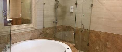 Un baño moderno con ducha de vidrio, lavamanos de mármol y una bañera grande.