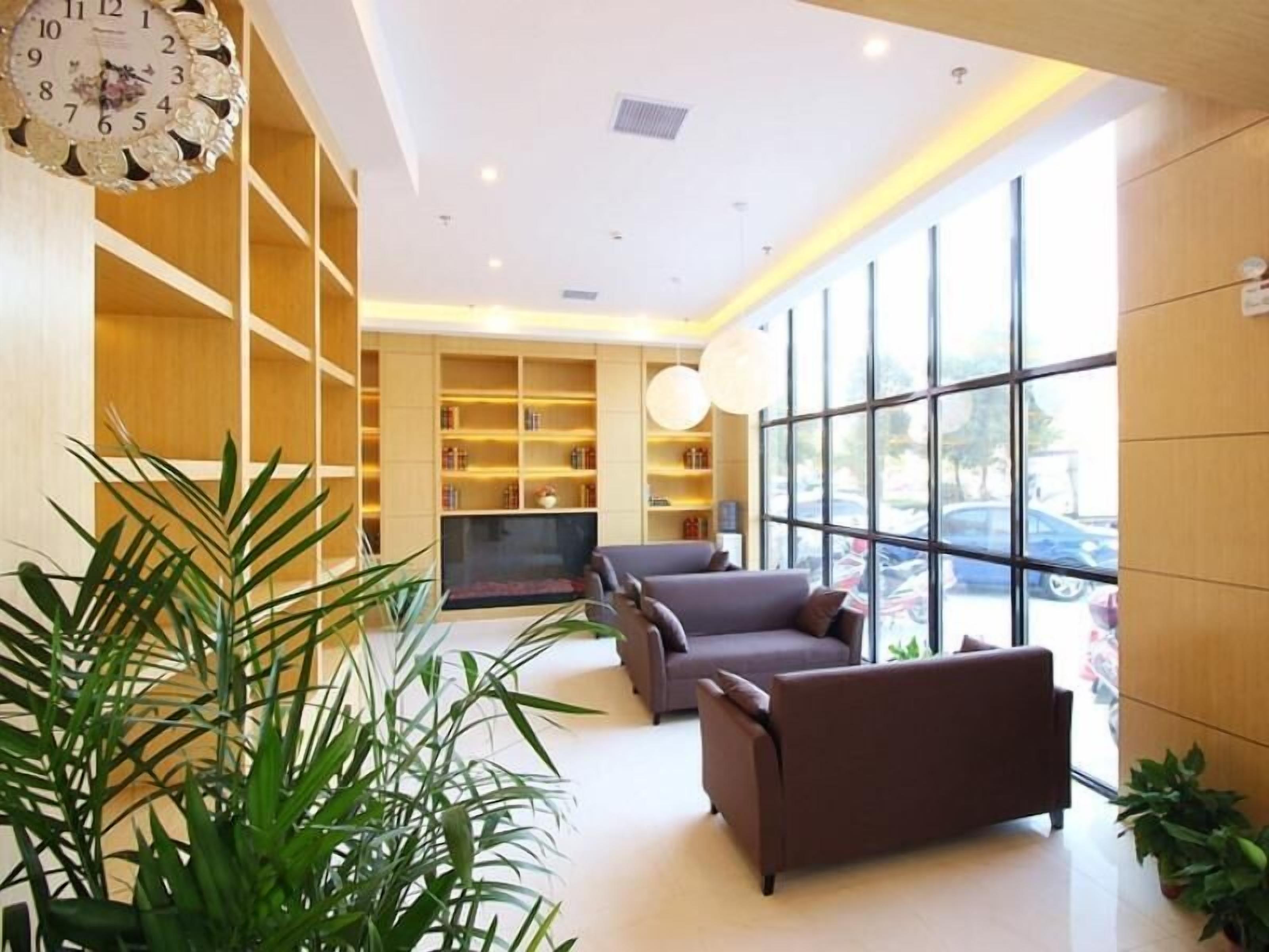Un hall moderno con un televisor grande, asientos cómodos y un ventanal con vistas al exterior.