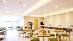 A spacious dining area with multiple tables and chairs, a buffet counter, and a clock on the wall. - Greentree Inn Wuxi Huishan High-speed Rail Qianzhou Chongwen Road Hotel (Wuxi)