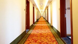 A hotel corridor with a carpeted floor, doors on both sides, and a ceiling light fixture. - Greentree Inn Wuxi Huishan High-speed Rail Qianzhou Chongwen Road Hotel (Wuxi)