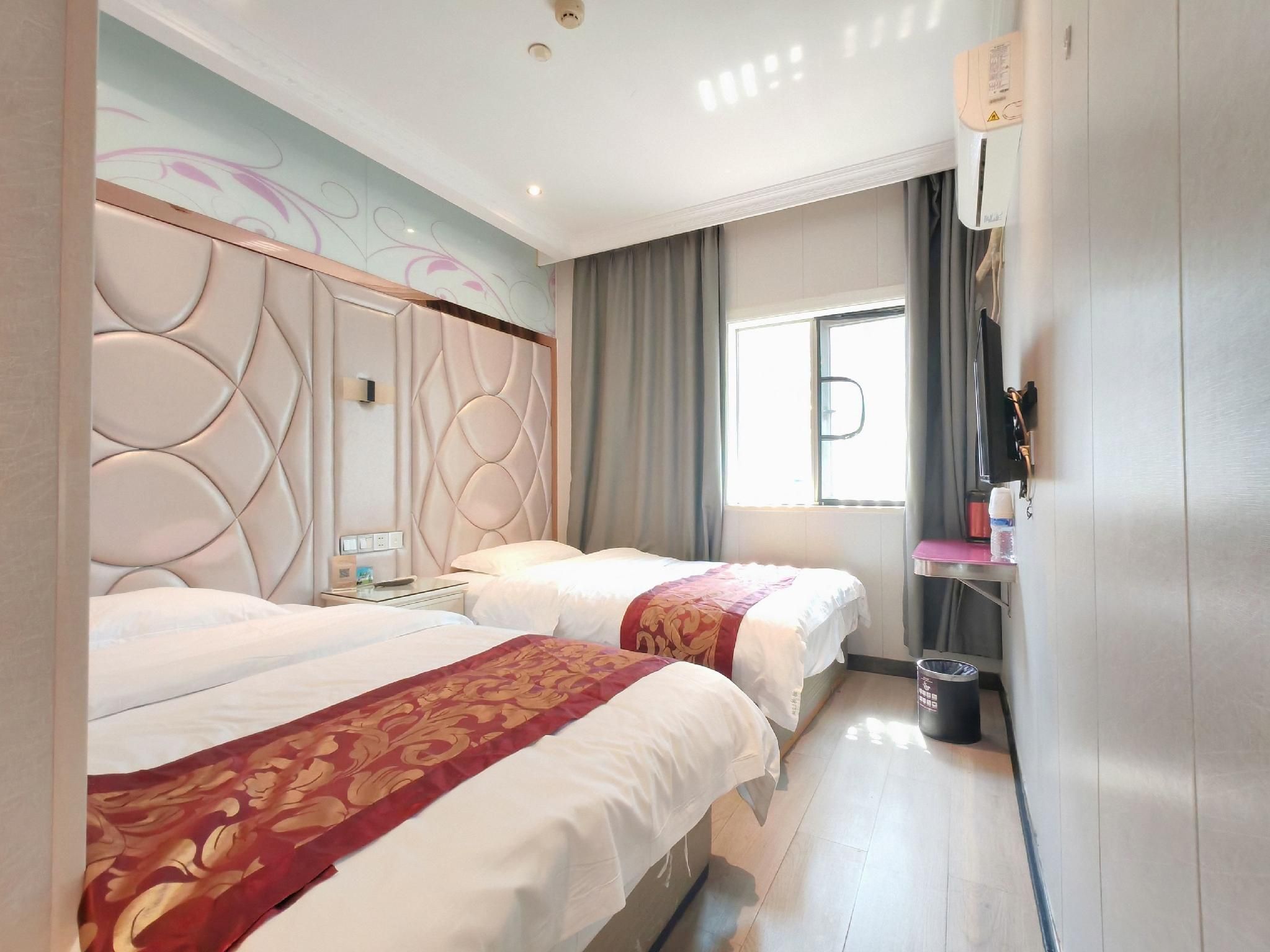 A hotel room with two beds, a large window, a flat-screen TV, and a minibar.