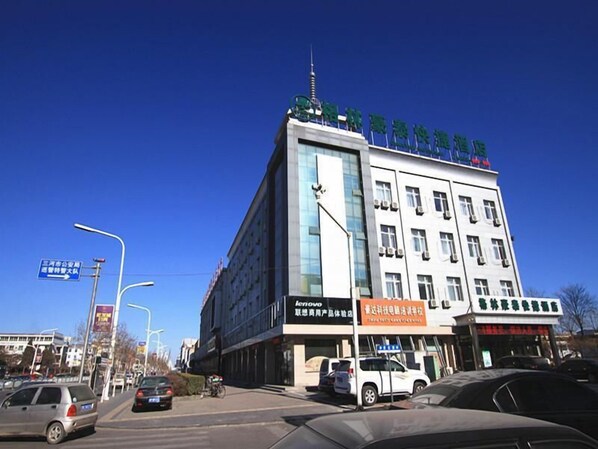 A multi-story building with commercial signage, a clear blue sky, and vehicles on the street. - Greentree Inn Langfang Sanhe South Yingbin Road Express Hotel (Langfang)