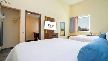 Ein Hotelzimmer mit zwei Betten, einem Fernseher, einem Kleiderschrank, einem Spiegel und einem fenster mit Vorhängen.