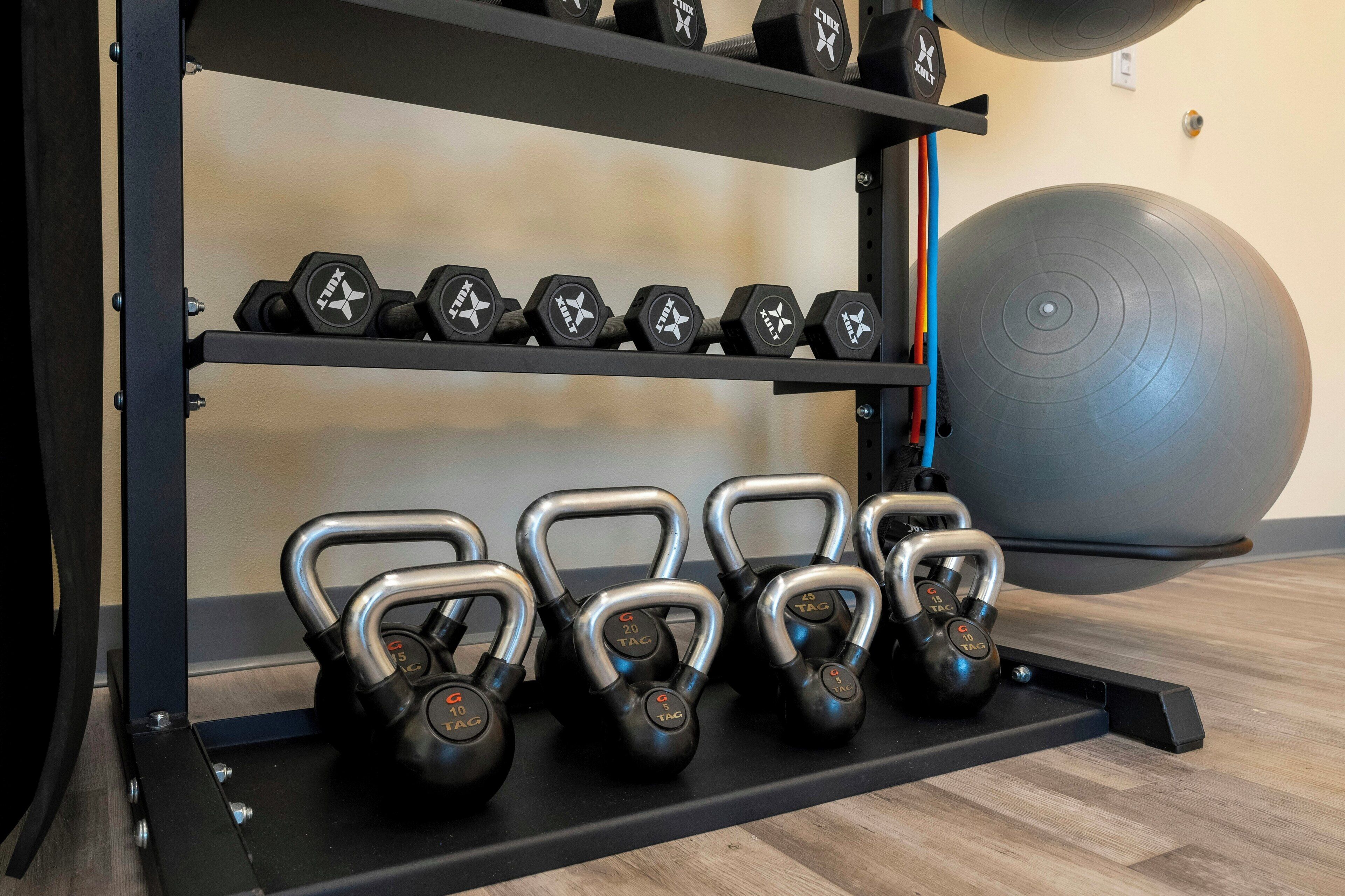 Ein Fitnessraum mit Kettlebells, Kurzhanteln und einem großen Trainingsball.