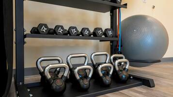 Ein Fitnessraum mit Kettlebells, Kurzhanteln und einem großen Trainingsball.