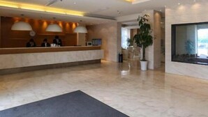Eine Hotelrezeption mit Marmorboden, einem Empfangstresen und einem großen Fenster.