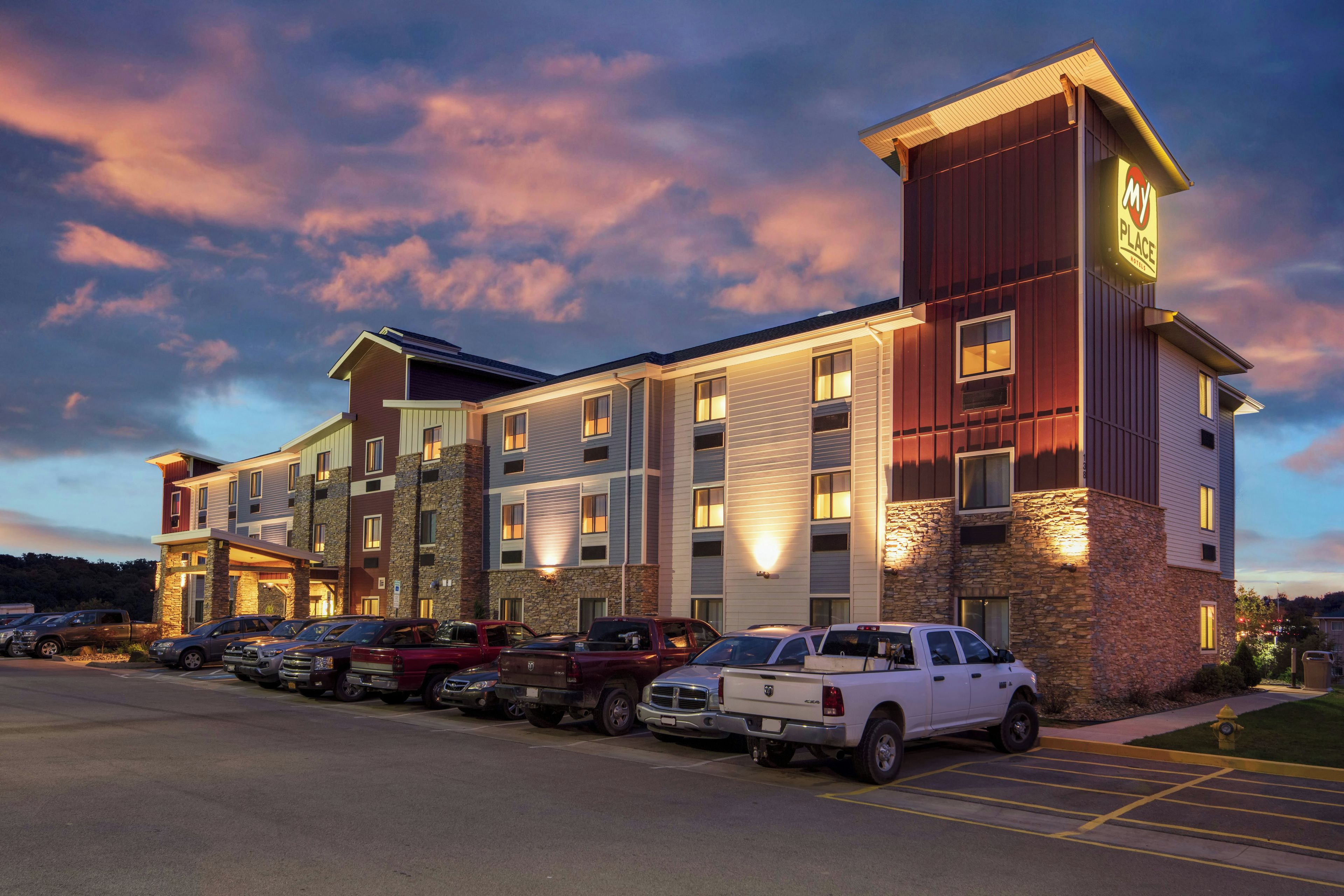 A multi-story hotel with a parking lot filled with vehicles.