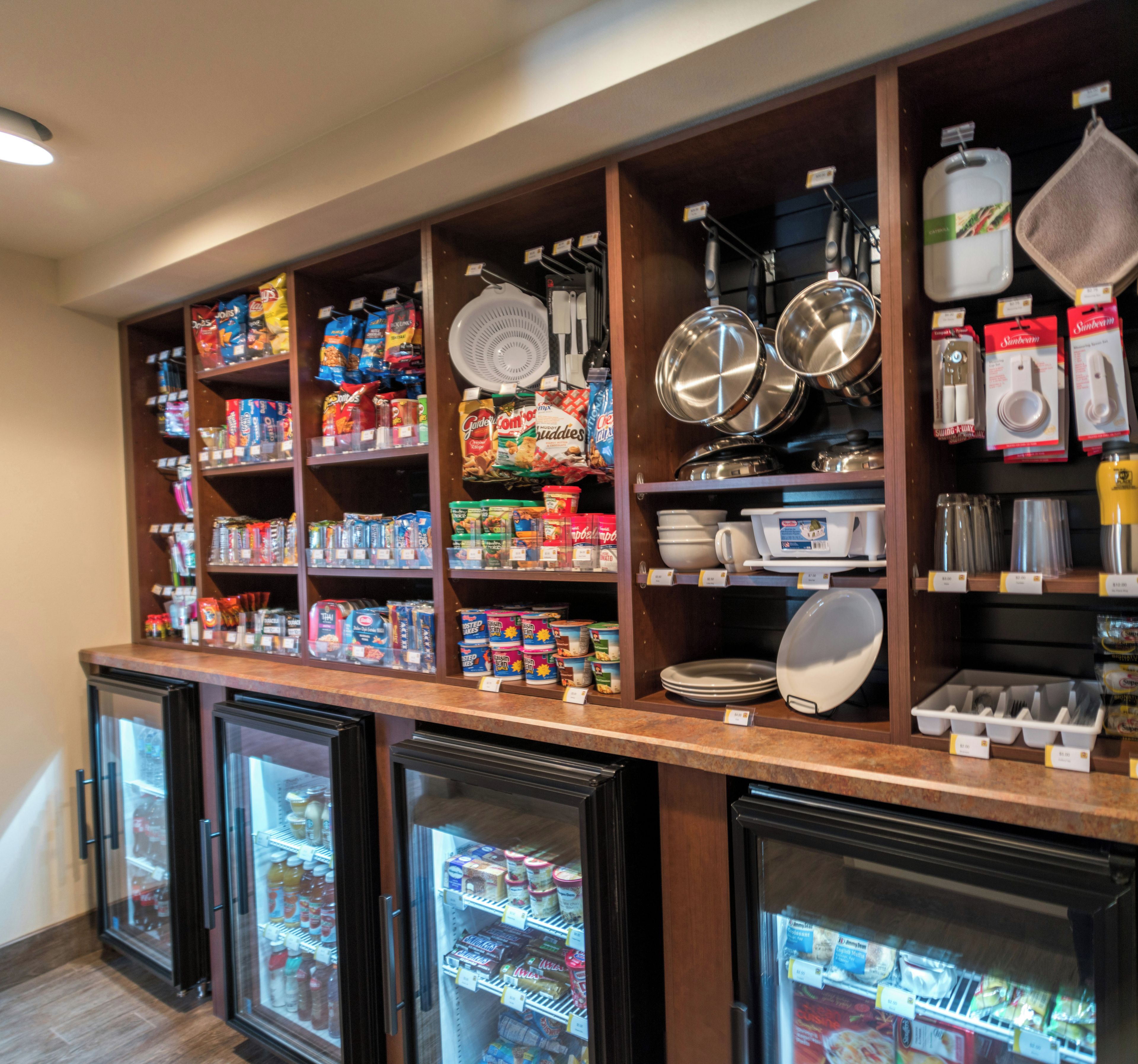 Un espace cuisine doté d’étagères remplies de produits alimentaires, d’ustensiles de cuisine et de vaisselle.