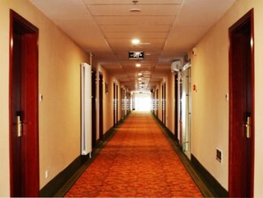 A hotel corridor with doors on both sides, carpeted flooring, and a sign overhead. - Greentree Inn Shandong Weifang Linqu Zhanqian Road Luchuan Business Hotel (Weifang)