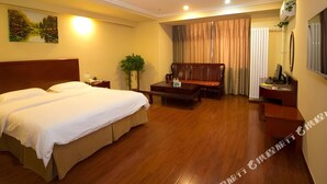 A hotel room with a large bed, a wooden sofa, a small table, and a desk with a chair. - Greentree Inn Shandong Weifang Linqu Zhanqian Road Luchuan Business Hotel (Weifang)