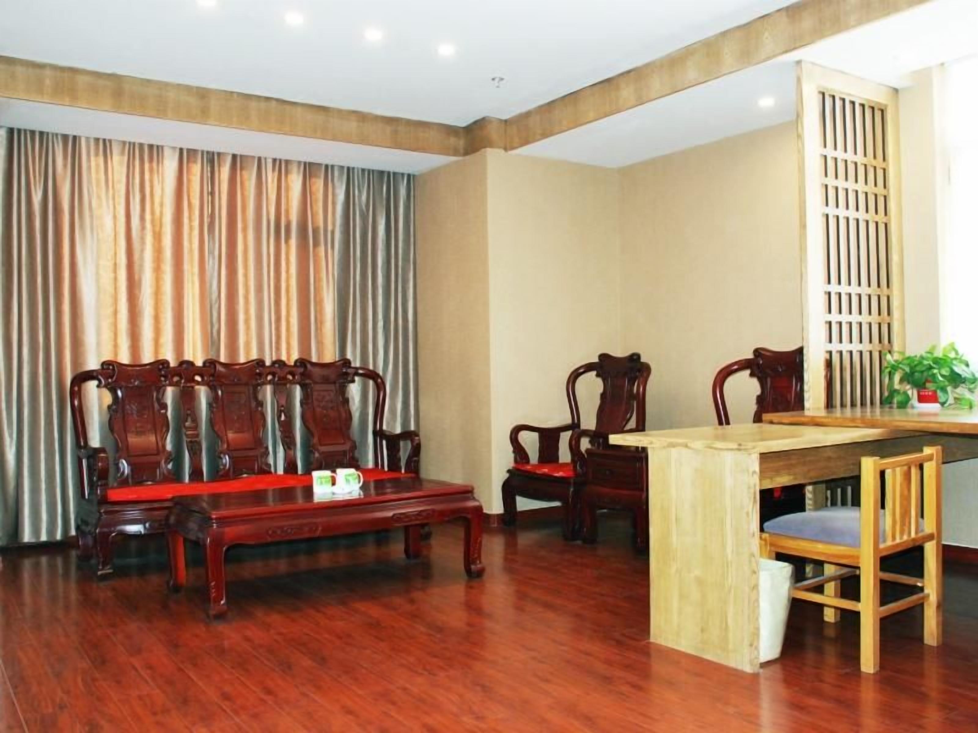 A room with a wooden dining table, four wooden chairs, a sofa, and a curtain.