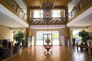 Eine geräumige Lobby mit hoher Decke, Holzbalken und einer zentral platzierten Zierpflanze.