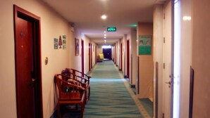 A hotel corridor with a carpeted floor, wooden benches, and doors on both sides. - Greentree Inn Jining Jinxiang Kuixing Road Express Hotel (Jining)