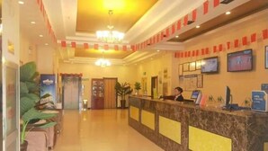 A hotel reception area with a marble counter, a receptionist, and a television screen.