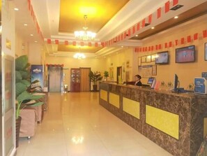 A hotel reception area with a marble counter, a receptionist, and a television screen. - Greentree Inn Tianjin Xiqing District Zhongbei Down Xiqing Road Shell Hotel (Tianjin)