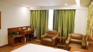 A hotel room with a desk, two leather chairs, a small round table, and a bed. - Vatica Hefei Jingshang International Trade City Hotel (Hefei)