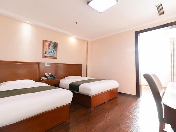 A hotel room with two beds, a painting on the wall, a desk, and a chair. - Greentree Inn Tangshan Caofeidian Free Trade Zone Municipal Building Express Hotel (Tangshan)